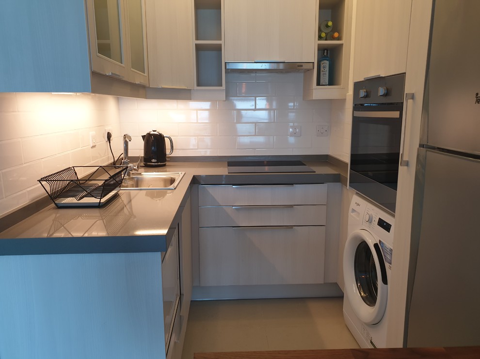 Example of a small minimalist u-shaped kitchen pantry design with a single-bowl sink, flat-panel cabinets, white cabinets, granite countertops, white backsplash, subway tile backsplash, stainless steel appliances and gray countertops