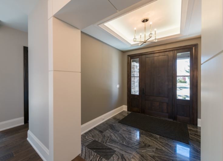 Photo of a transitional foyer in Toronto with a dark wood front door, marble floors, grey walls and a single front door.