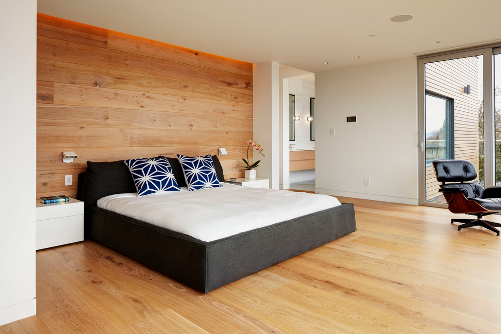 This is an example of a large contemporary master bedroom in Vancouver with white walls and light hardwood floors.