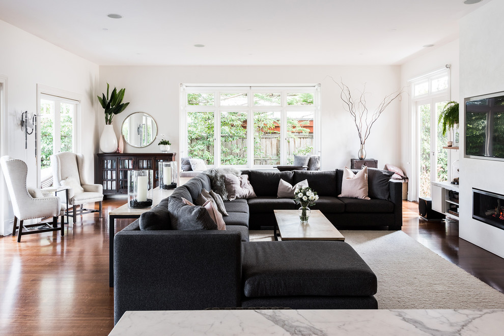 Photo of a mid-sized contemporary open concept living room in Melbourne with white walls, dark hardwood floors, a standard fireplace, a plaster fireplace surround, a wall-mounted tv and brown floor.