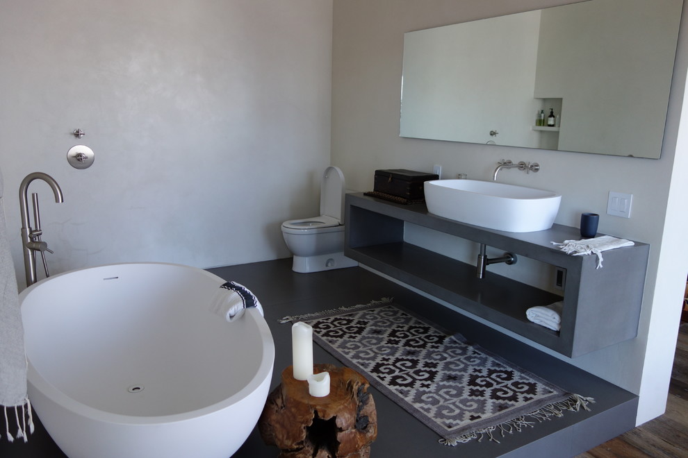 Mid-sized modern master bathroom in San Francisco with open cabinets, grey cabinets, a freestanding tub, an open shower, a one-piece toilet, a vessel sink, white walls, concrete floors and concrete benchtops.