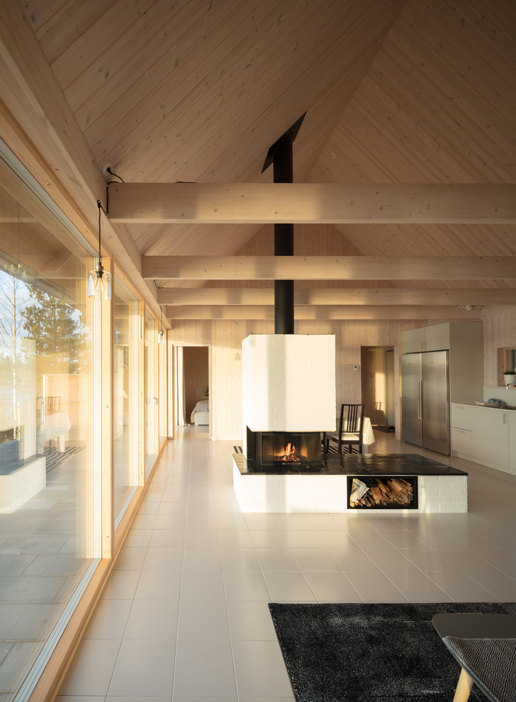 This is an example of a mid-sized scandinavian open concept living room in Other with ceramic floors, a two-sided fireplace, a brick fireplace surround, no tv and beige floor.