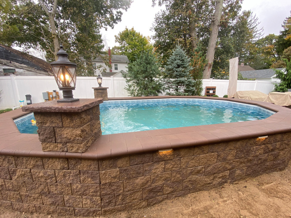 Photo of a large traditional backyard custom-shaped aboveground pool in New York with with a pool and concrete pavers.
