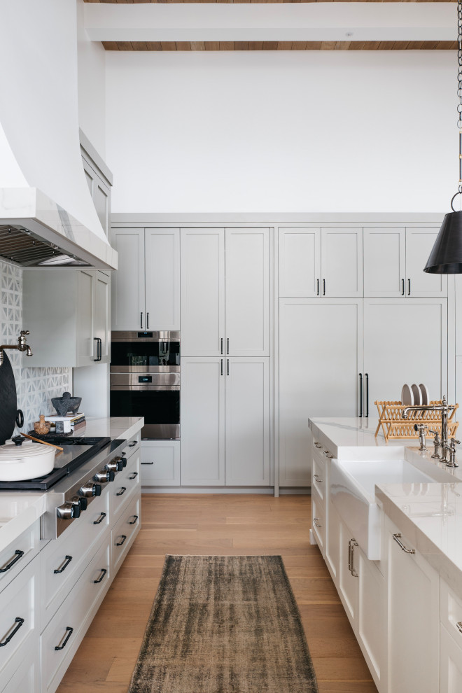 Inspiration for a large transitional galley light wood floor, beige floor and wood ceiling open concept kitchen remodel in Phoenix with a farmhouse sink, recessed-panel cabinets, white cabinets, marble countertops, white backsplash, marble backsplash, stainless steel appliances, an island and white countertops