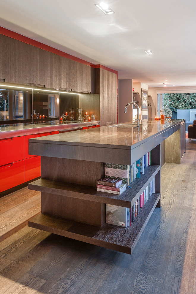 Inspiration for a mid-sized contemporary single-wall eat-in kitchen in Auckland with an undermount sink, flat-panel cabinets, orange cabinets, solid surface benchtops, black splashback, glass sheet splashback, black appliances, dark hardwood floors, with island, brown floor and brown benchtop.