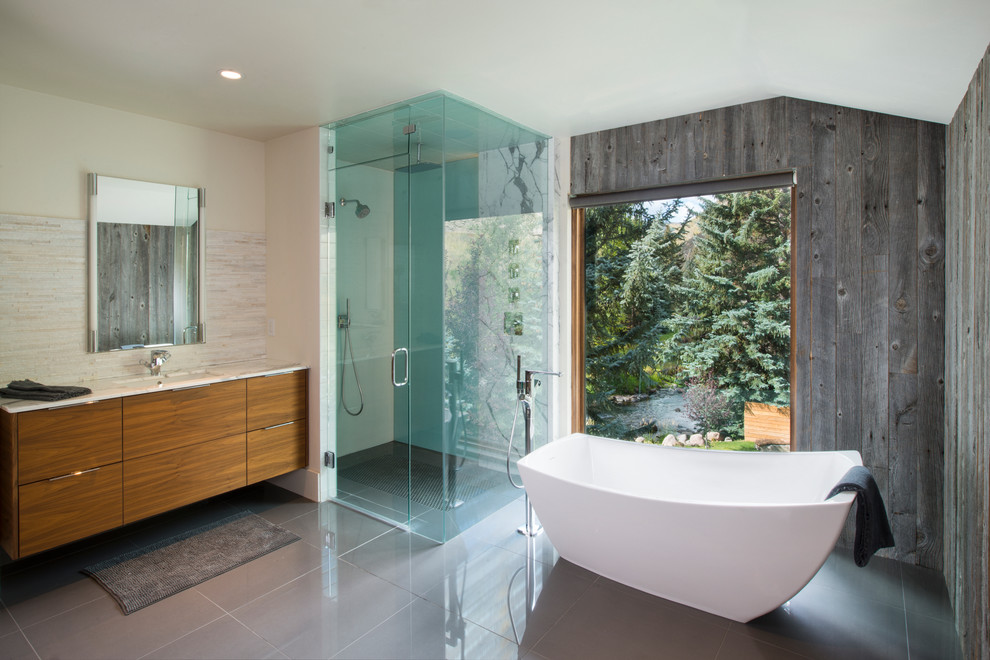 Contemporary bathroom in Denver with flat-panel cabinets, medium wood cabinets, a freestanding tub, a corner shower, beige tile, gray tile, white walls, an undermount sink and a hinged shower door.
