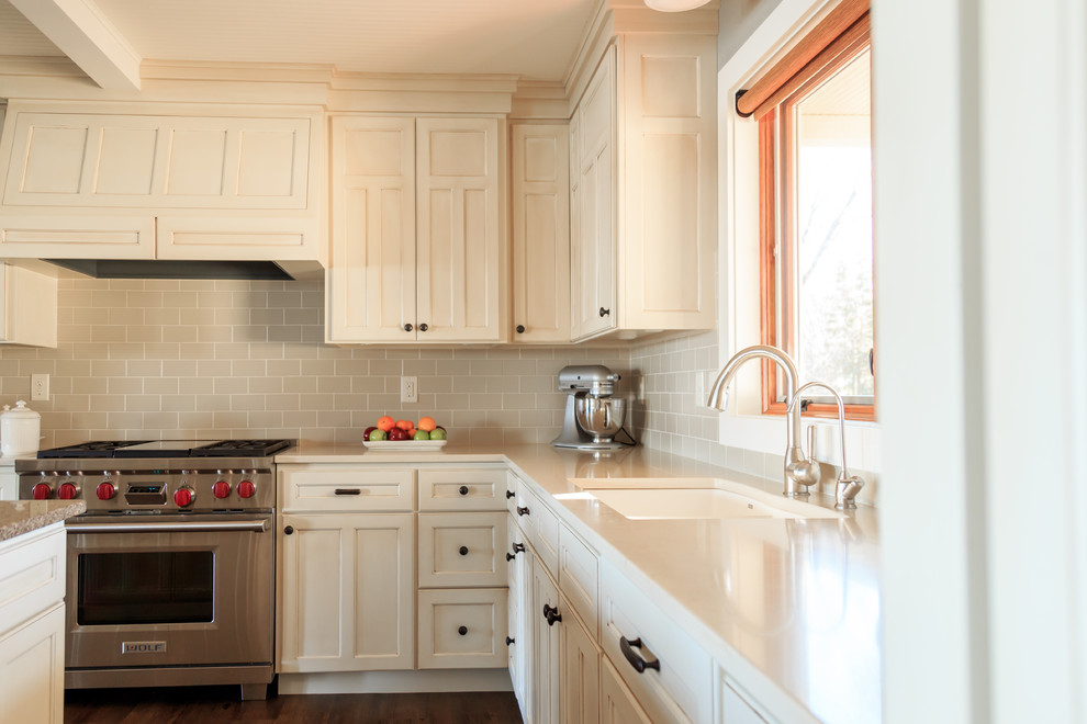 Transitional l-shaped vinyl floor open concept kitchen photo in Minneapolis with an undermount sink, raised-panel cabinets, white cabinets, quartz countertops, beige backsplash, ceramic backsplash, paneled appliances and an island