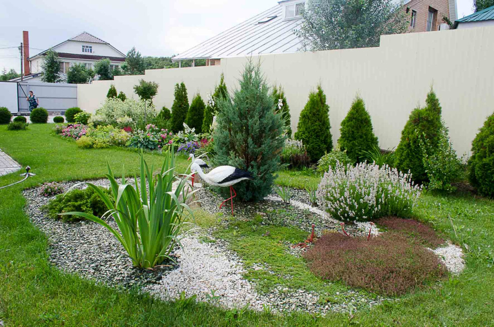 Immagine di un piccolo giardino stile marinaro esposto in pieno sole davanti casa in estate con pacciame e recinzione in metallo
