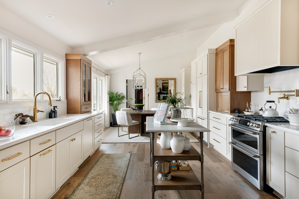 Example of a mid-sized transitional galley medium tone wood floor, brown floor and vaulted ceiling eat-in kitchen design in Minneapolis with an undermount sink, shaker cabinets, quartz countertops, white backsplash, subway tile backsplash, stainless steel appliances, an island and white countertops