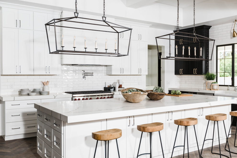 Transitional l-shaped dark wood floor and brown floor kitchen photo in Phoenix with shaker cabinets, white cabinets, white backsplash, subway tile backsplash, stainless steel appliances, an island and white countertops