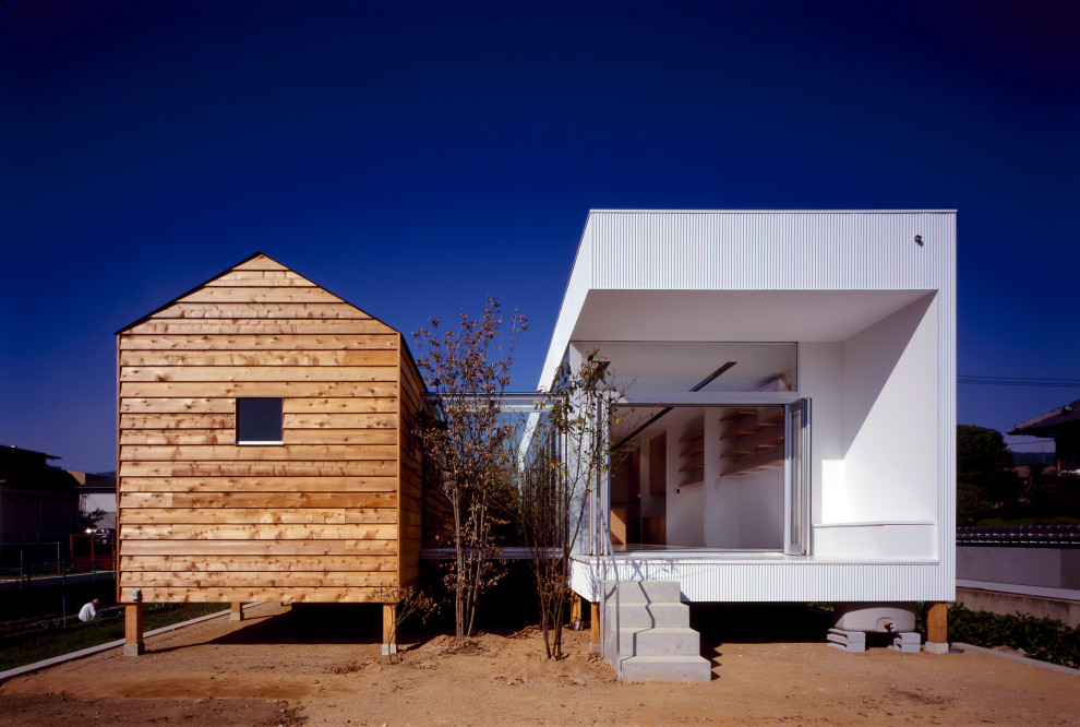 Immagine della villa bianca moderna a un piano con rivestimento in metallo, tetto piano, tetto grigio e pannelli e listelle di legno