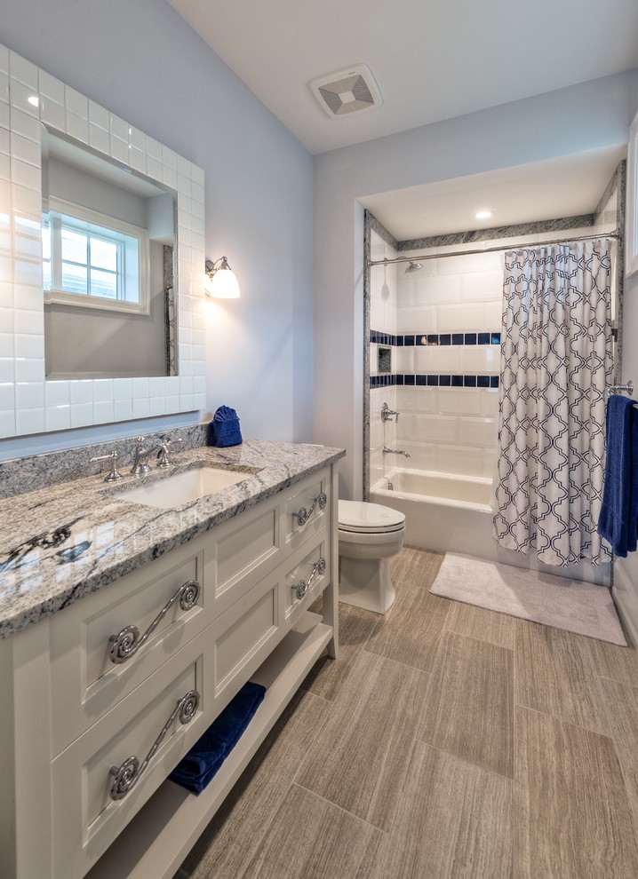 This is an example of a mid-sized beach style kids bathroom in Miami with open cabinets, dark wood cabinets, an alcove tub, an alcove shower, a one-piece toilet, gray tile, porcelain tile, porcelain floors, an undermount sink and marble benchtops.