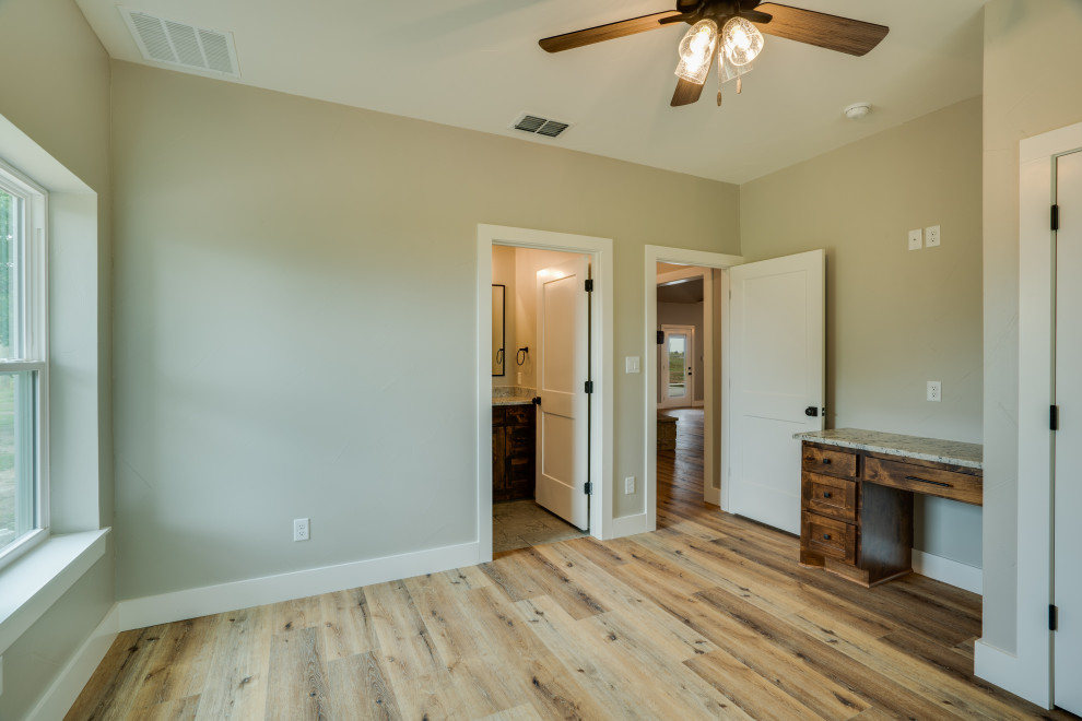 Mid-sized country master medium tone wood floor, brown floor and vaulted ceiling bedroom photo in Dallas with gray walls