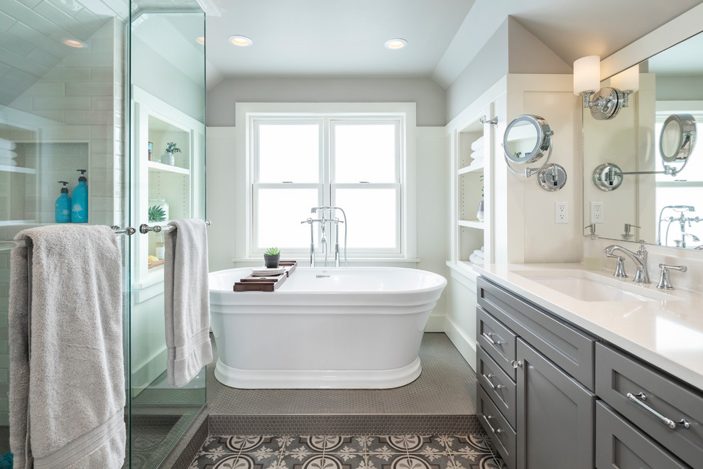 Inspiration for a mid-sized transitional master gray floor and porcelain tile freestanding bathtub remodel in Seattle with shaker cabinets, gray cabinets, gray walls, an undermount sink, quartz countertops, a hinged shower door and white countertops