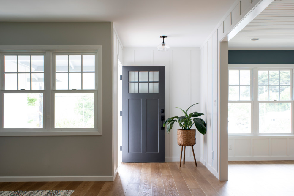 Ejemplo de puerta principal clásica renovada grande con paredes blancas, suelo de madera en tonos medios, puerta simple, puerta azul, suelo marrón, machihembrado y boiserie