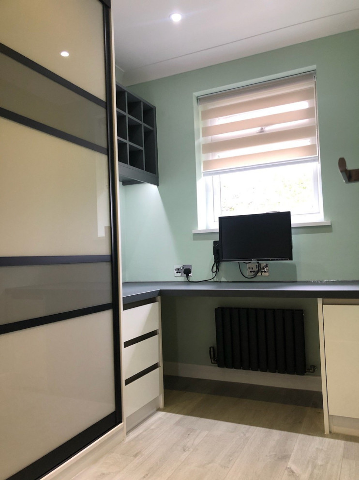 Modern inredning av ett litet arbetsrum, med gröna väggar, ljust trägolv, ett inbyggt skrivbord och brunt golv