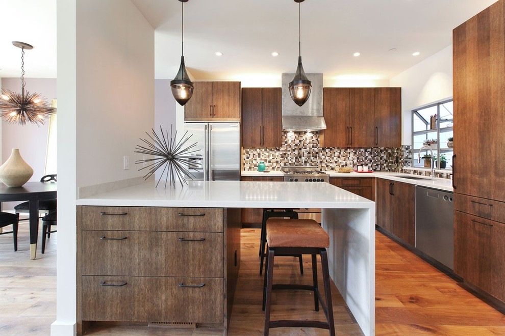 Photo of a contemporary l-shaped eat-in kitchen in San Francisco with a double-bowl sink, flat-panel cabinets, dark wood cabinets, multi-coloured splashback, mosaic tile splashback, stainless steel appliances, medium hardwood floors and a peninsula.