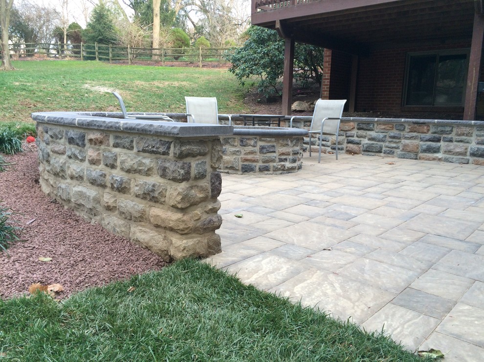 This is an example of a mid-sized country backyard patio in Wilmington with concrete pavers, no cover and a fire feature.