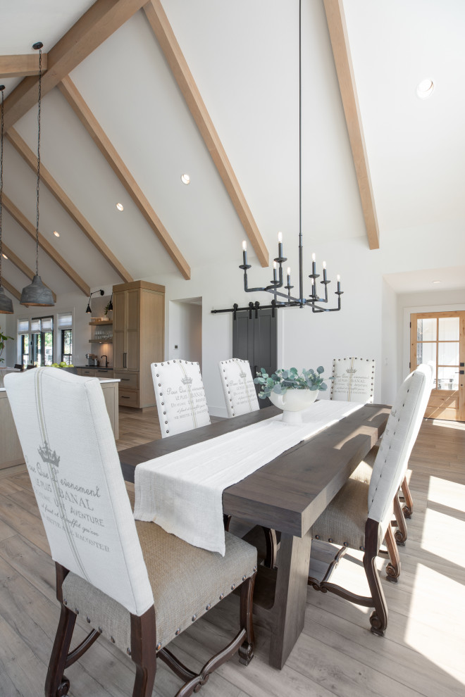 Design ideas for an expansive rural kitchen/dining room in Portland with white walls, vinyl flooring, a standard fireplace, a plastered fireplace surround, brown floors and exposed beams.