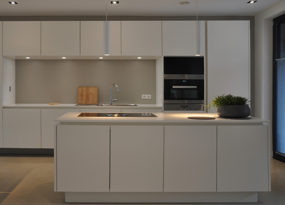 Foto di una cucina contemporanea di medie dimensioni con ante lisce, ante bianche, paraspruzzi bianco e pavimento in cemento