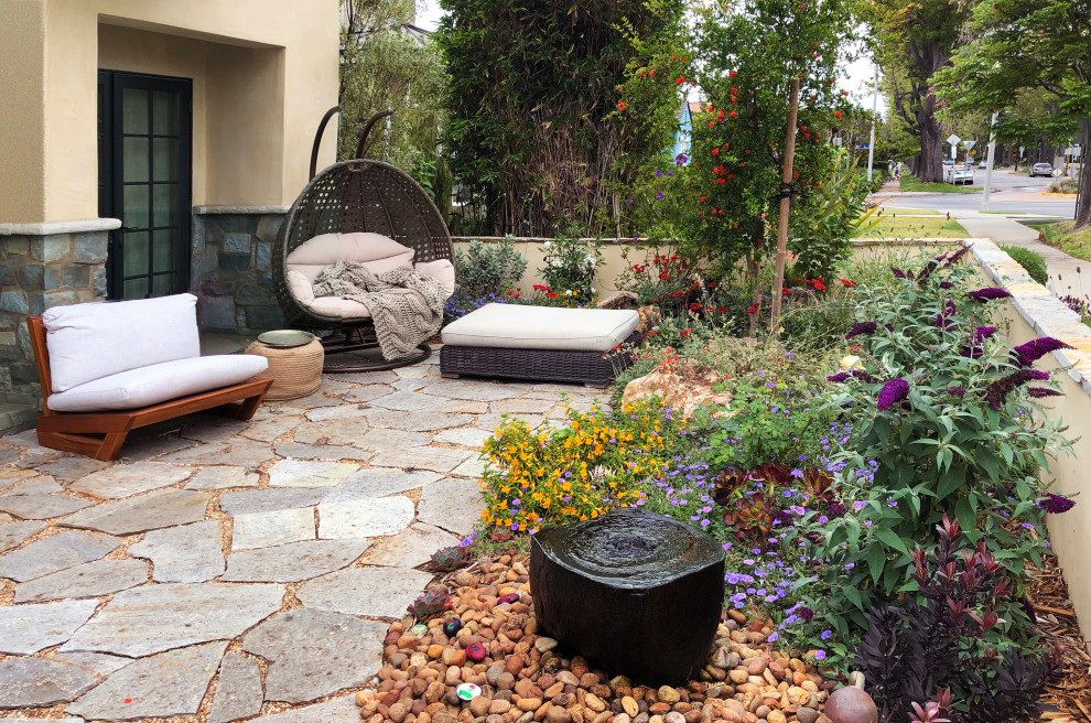 Idee per un piccolo giardino xeriscape bohémian esposto in pieno sole davanti casa in primavera con pavimentazioni in pietra naturale e recinzione in pietra