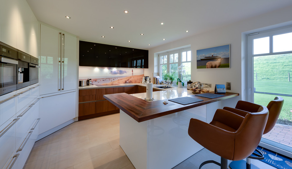 Mid-sized contemporary u-shaped separate kitchen in Hamburg with an undermount sink, flat-panel cabinets, white cabinets, multi-coloured splashback, glass sheet splashback, panelled appliances, a peninsula, beige floor and cement tiles.
