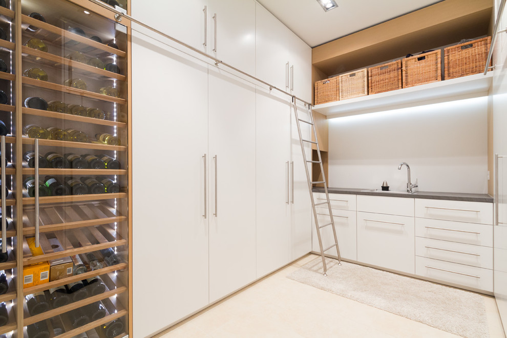 Large contemporary single-wall utility room in Hamburg with a drop-in sink, flat-panel cabinets, white cabinets, white walls and a concealed washer and dryer.