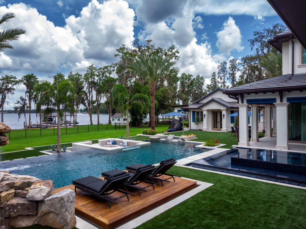 Esempio di una grande piscina a sfioro infinito design personalizzata dietro casa con paesaggistica bordo piscina e piastrelle