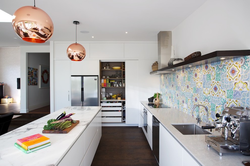 Photo of a large contemporary l-shaped open plan kitchen in Auckland with a single-bowl sink, white cabinets, marble benchtops, multi-coloured splashback, ceramic splashback, stainless steel appliances, dark hardwood floors, with island and flat-panel cabinets.