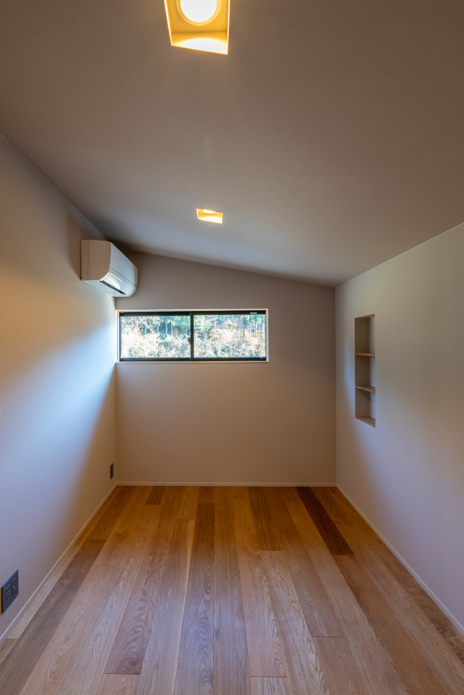 Modern inredning av ett könsneutralt tonårsrum kombinerat med skrivbord, med vita väggar, mellanmörkt trägolv och brunt golv