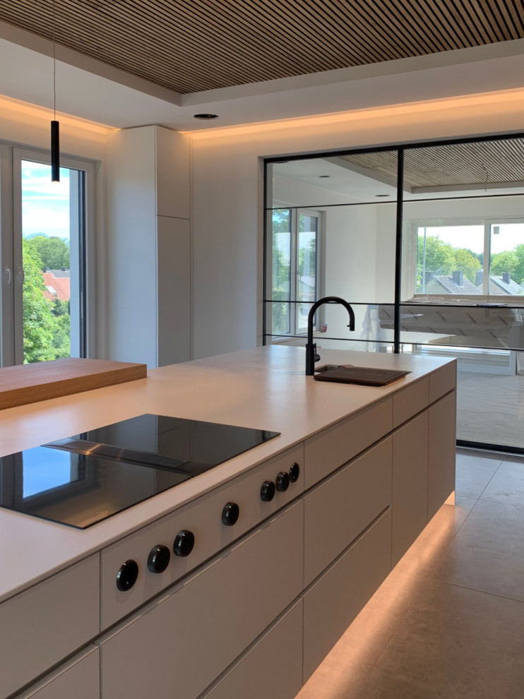 Industrial Küche mit flächenbündigen Schrankfronten, Mineralwerkstoff-Arbeitsplatte, Kücheninsel und weißer Arbeitsplatte in Essen