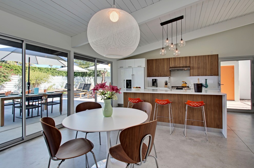 Mid-sized 1960s open concept concrete floor dining room photo in Los Angeles with a bar, white walls, a standard fireplace, a tile fireplace and a wall-mounted tv