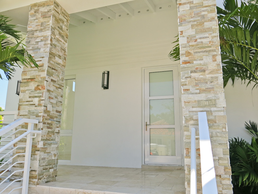 Design ideas for a contemporary beige house exterior in Miami with stone veneer.