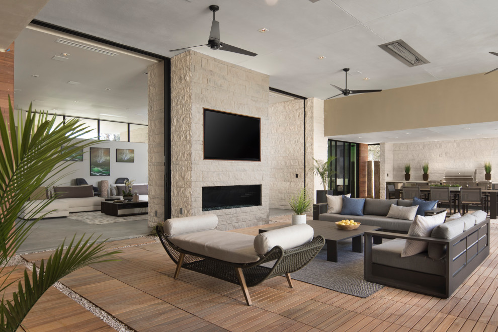 This is an example of an expansive contemporary open concept living room in Las Vegas with multi-coloured walls, porcelain floors, a two-sided fireplace, a brick fireplace surround, a wall-mounted tv and grey floor.