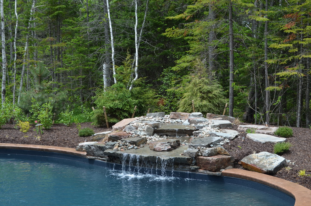 Example of a large mountain style backyard stamped concrete and freeform natural pool design