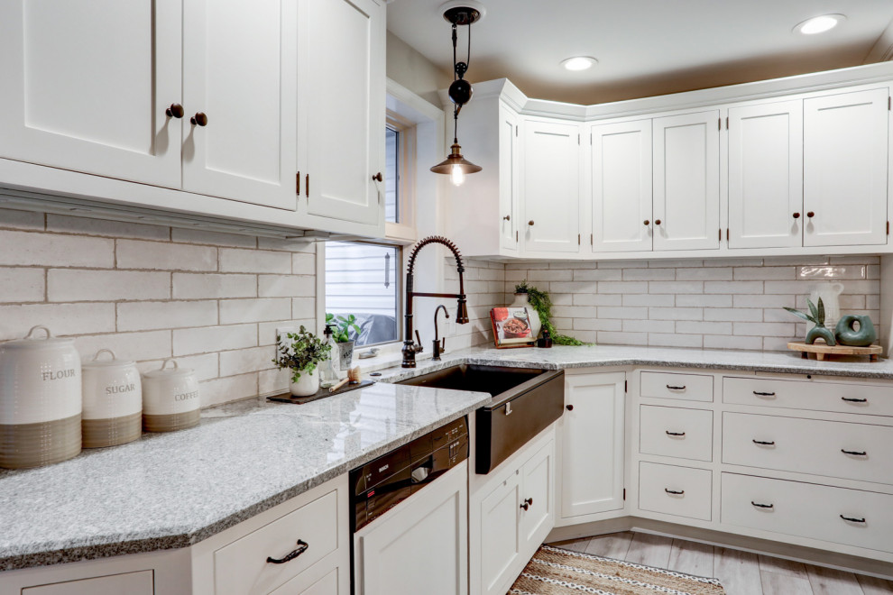 Exempel på ett avskilt, mellanstort klassiskt grå grått l-kök, med en rustik diskho, luckor med infälld panel, vita skåp, granitbänkskiva, vitt stänkskydd, stänkskydd i keramik, rostfria vitvaror, vinylgolv, en köksö och grått golv