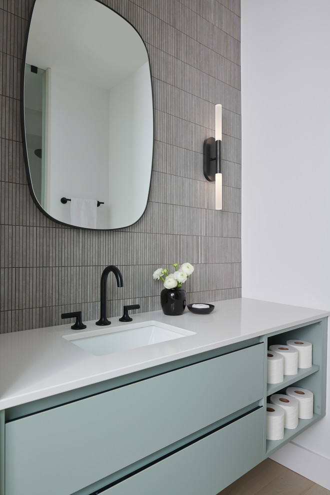 Photo of a mid-sized contemporary 3/4 bathroom in Toronto with flat-panel cabinets, blue cabinets, an alcove shower, a one-piece toilet, gray tile, matchstick tile, white walls, light hardwood floors, an undermount sink, engineered quartz benchtops, beige floor, a hinged shower door, white benchtops, a single vanity and a floating vanity.