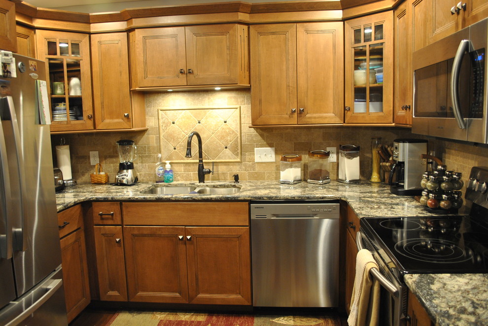Inspiration for a brown floor kitchen remodel with brown cabinets, beige backsplash, stainless steel appliances, an island and gray countertops