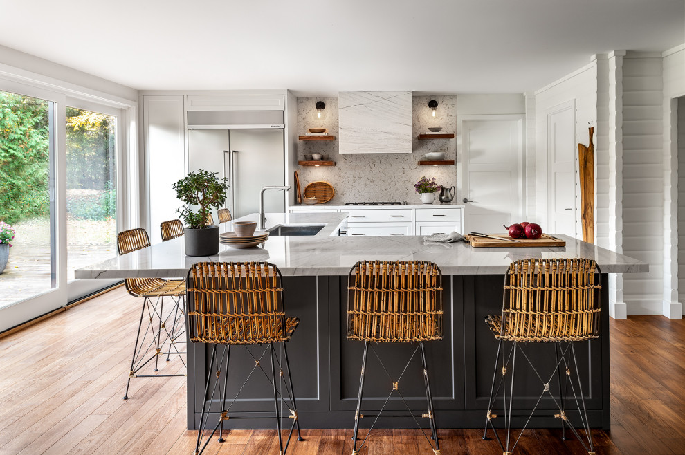 Mid-sized mountain style medium tone wood floor kitchen photo with a double-bowl sink, recessed-panel cabinets, gray cabinets, quartzite countertops, white backsplash, mosaic tile backsplash, stainless steel appliances, an island and white countertops