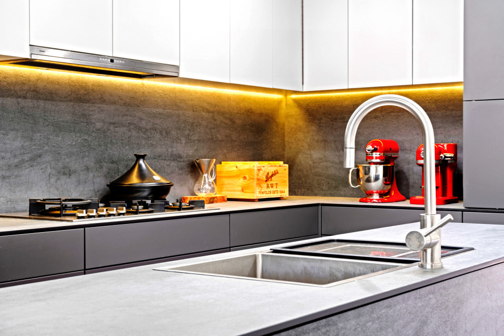 Photo of a mid-sized contemporary l-shaped kitchen in Sydney with a double-bowl sink, flat-panel cabinets, grey cabinets, grey splashback, porcelain splashback, stainless steel appliances, painted wood floors, with island, black floor and grey benchtop.