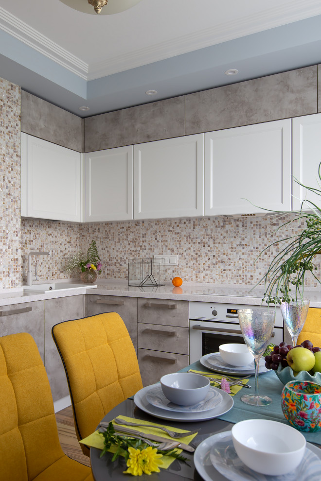 Mid-sized trendy l-shaped cork floor and yellow floor eat-in kitchen photo in Moscow with an undermount sink, raised-panel cabinets, white cabinets, solid surface countertops, beige backsplash, mosaic tile backsplash, white appliances, no island and white countertops