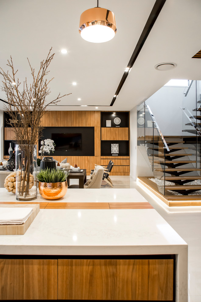 This is an example of a mid-sized modern galley open plan kitchen in Brisbane with recessed-panel cabinets, medium wood cabinets, solid surface benchtops, orange splashback, mirror splashback, panelled appliances, ceramic floors, with island and beige floor.