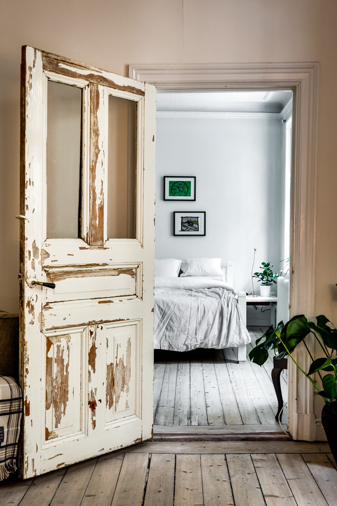 Design ideas for a mid-sized traditional bedroom in Stockholm with white walls and light hardwood floors.