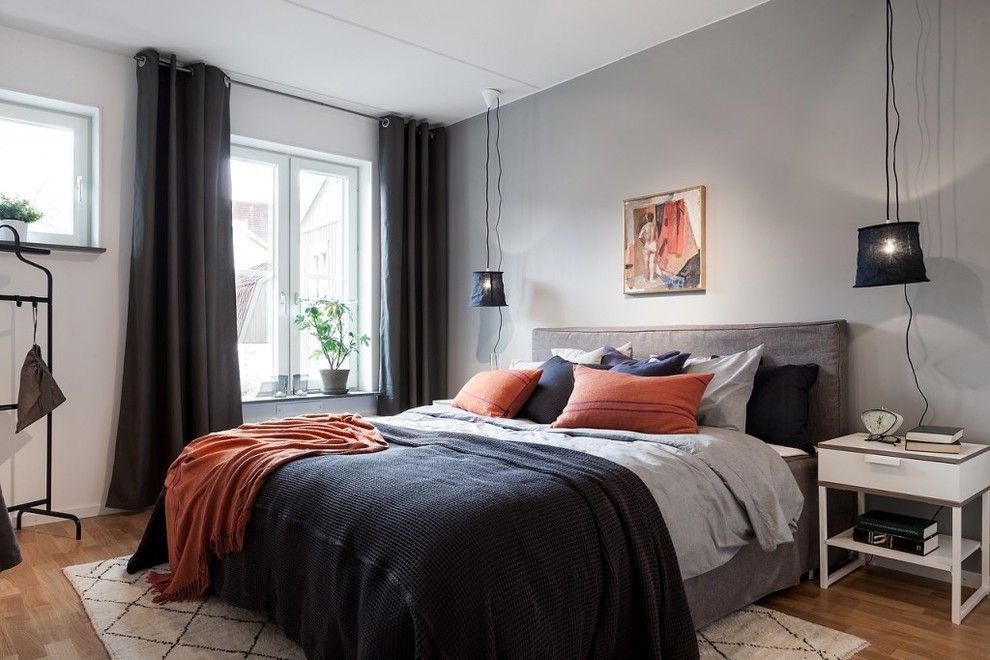 Mid-sized contemporary master bedroom in Stockholm with grey walls and medium hardwood floors.