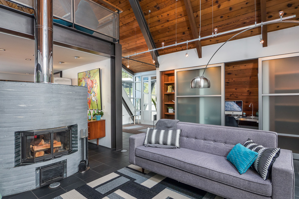 Inspiration for a mid-sized industrial loft-style living room in Seattle with white walls, slate floors, a two-sided fireplace, a stone fireplace surround and a freestanding tv.