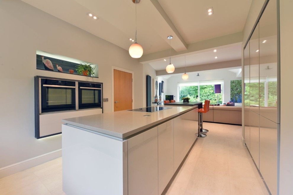 This is an example of a large contemporary kitchen in Manchester with an undermount sink, flat-panel cabinets, quartzite benchtops, beige splashback, stone slab splashback, stainless steel appliances, porcelain floors and with island.
