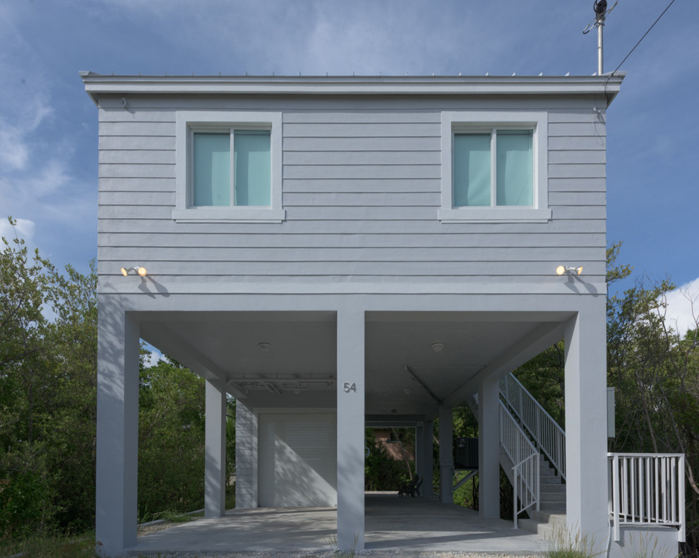 Inspiration for a large beach style one-storey blue exterior in Miami with wood siding and a flat roof.