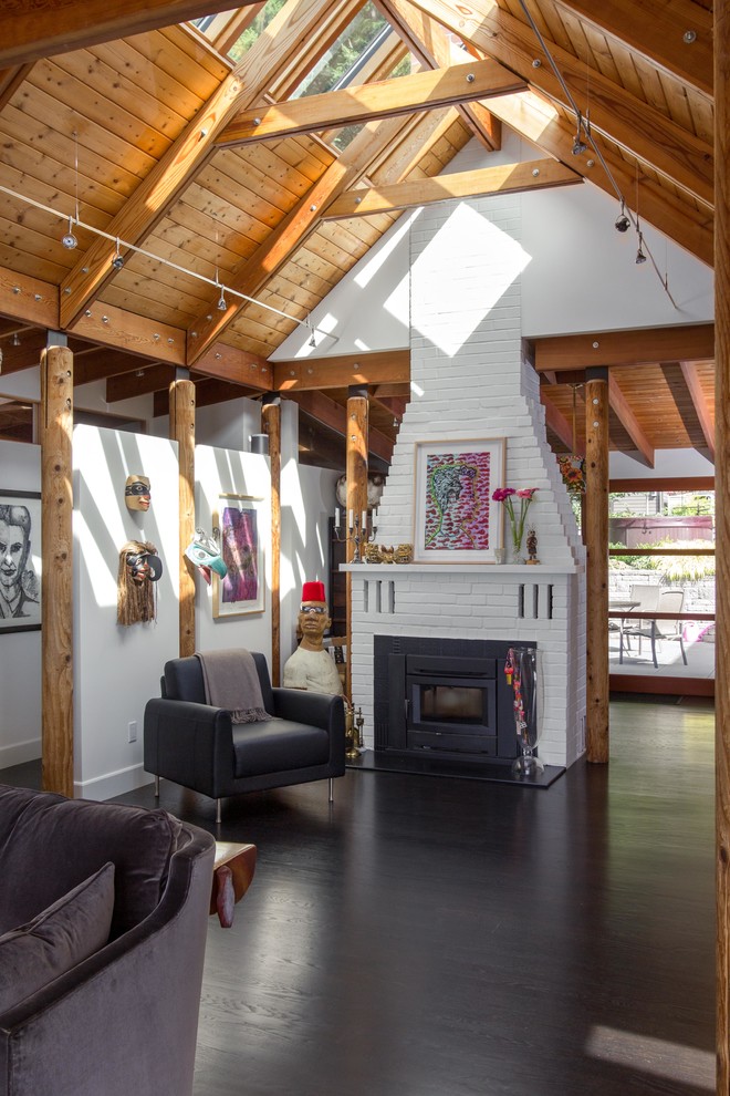 Photo of a mid-sized contemporary living room in Seattle with dark hardwood floors, a wood stove, black floor, white walls and a brick fireplace surround.