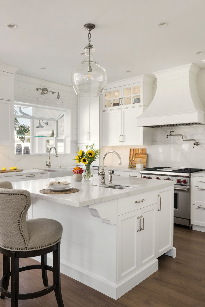 Inspiration for a mid-sized traditional u-shaped eat-in kitchen in San Diego with an undermount sink, recessed-panel cabinets, white cabinets, quartz benchtops, white splashback, engineered quartz splashback, stainless steel appliances, vinyl floors, with island, brown floor and white benchtop.