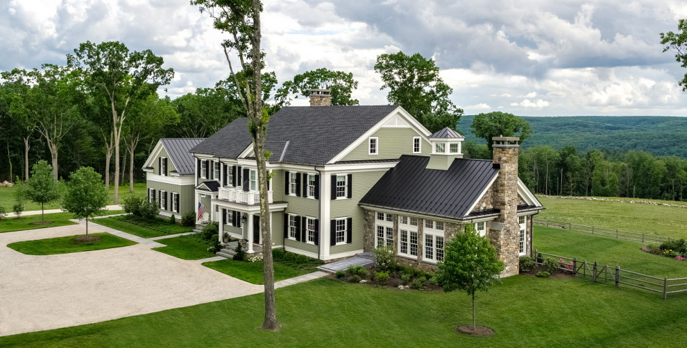 Пример оригинального дизайна: большой, двухэтажный, зеленый частный загородный дом в классическом стиле с облицовкой из камня, двускатной крышей, крышей из смешанных материалов, черной крышей и отделкой планкеном